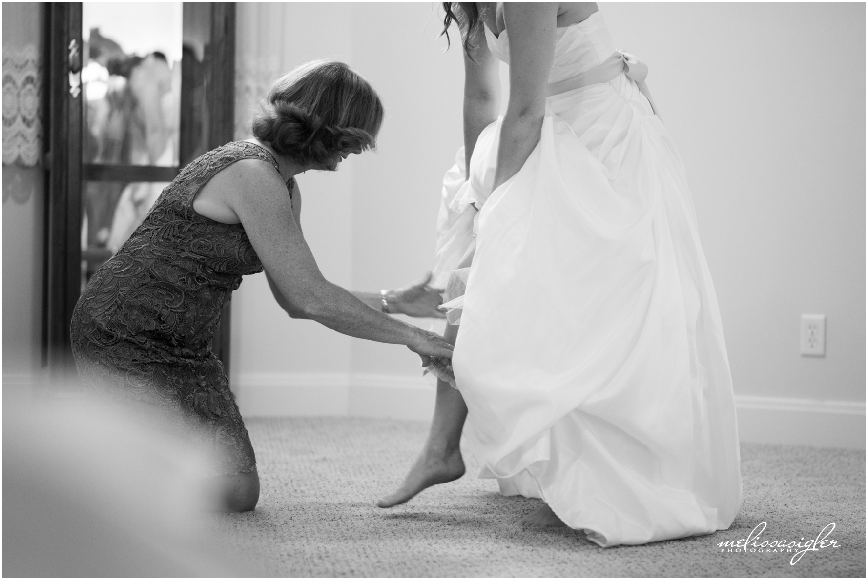 Mother of the bride helping bride with garter at Victorian Veranda by Lawrence Kansas wedding photographer Melissa Sigler