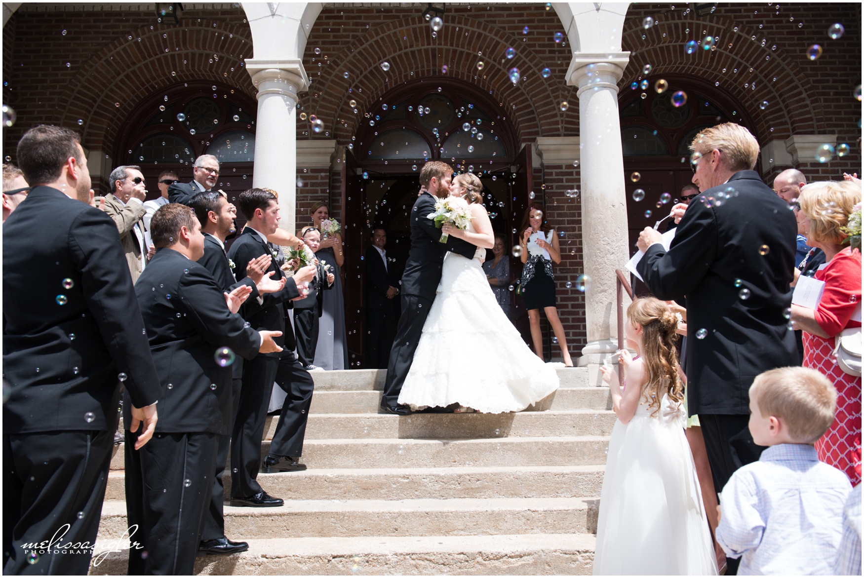 Wedding bubble exit in front of St Johns Catholic church in Lawrence Kansas by Melissa Sigler Photography