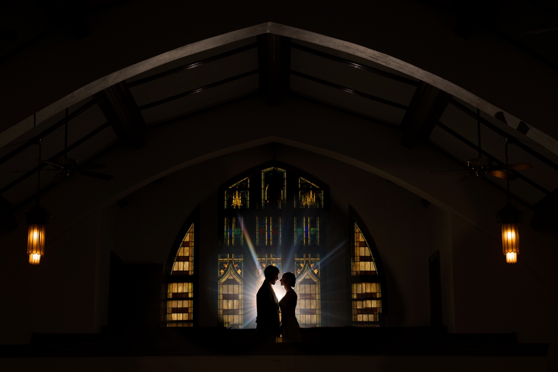 Dramatic bride and groom portrait in front of stained glass window