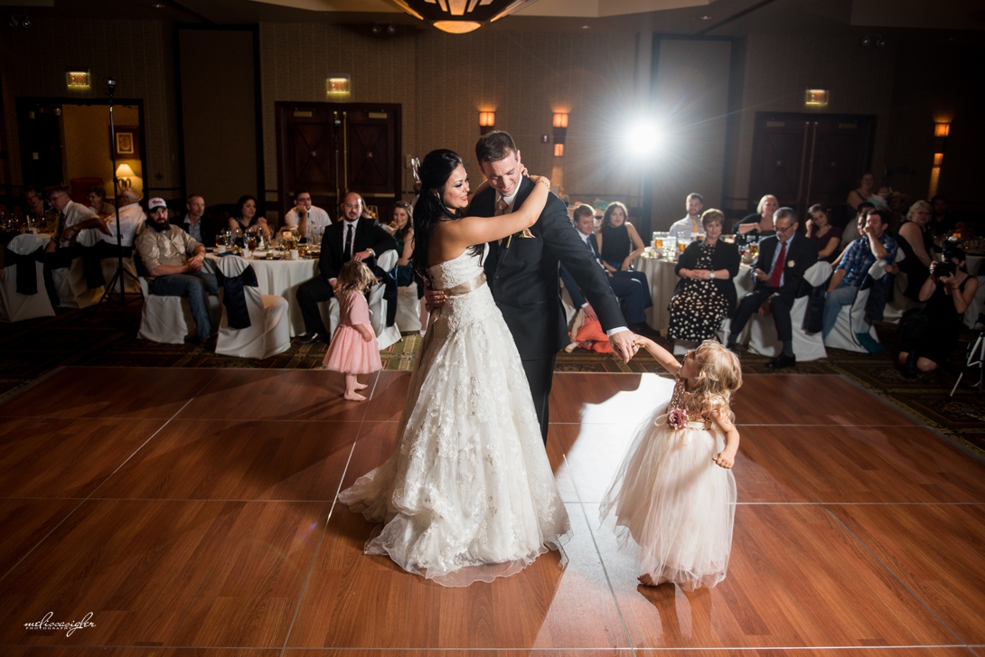 Flower girl dances with bride and groom