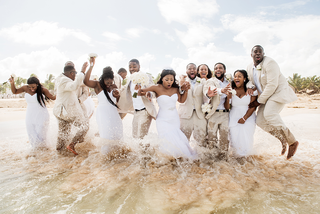 bridal party running into waves after beach wedding