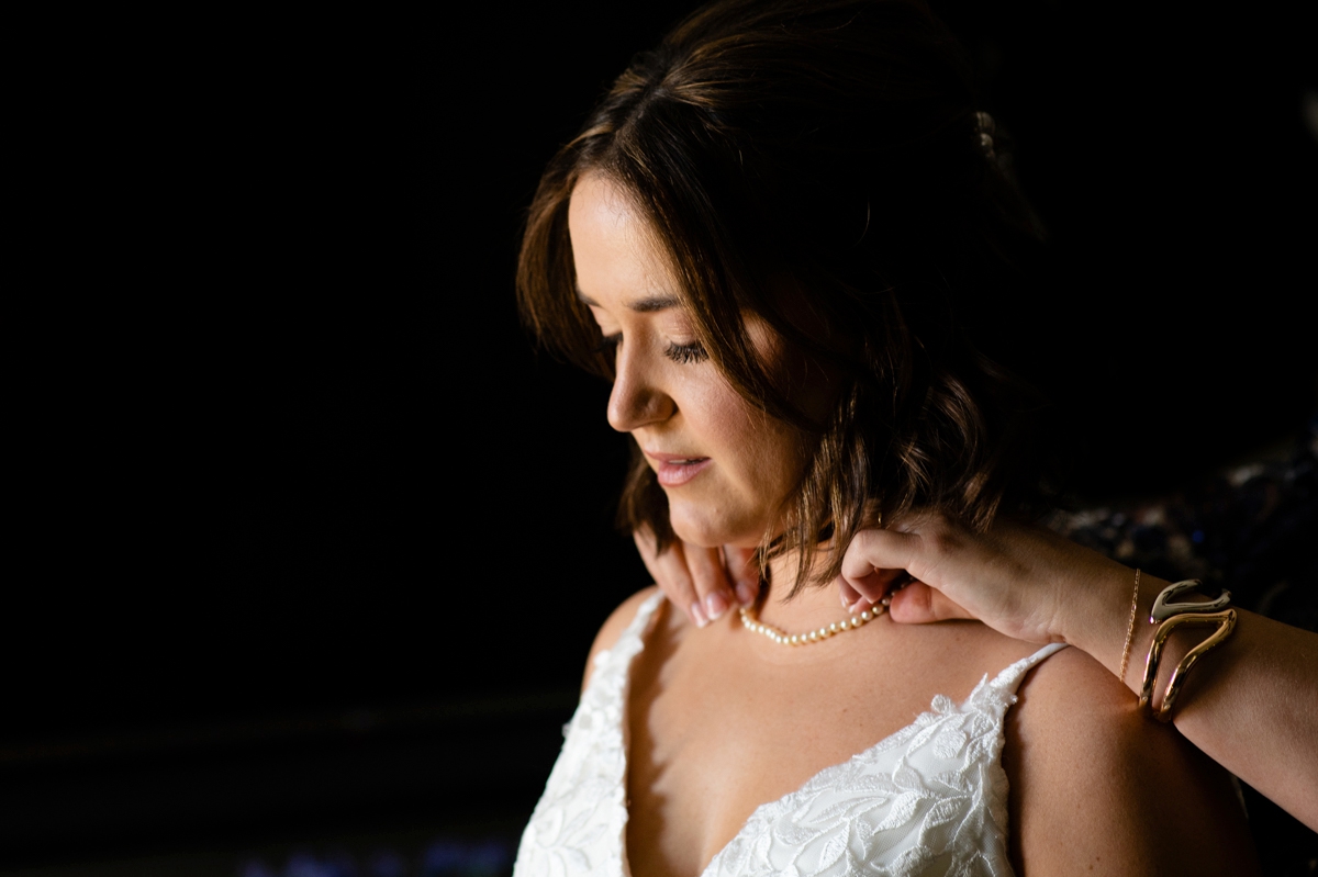 bride putting on necklace